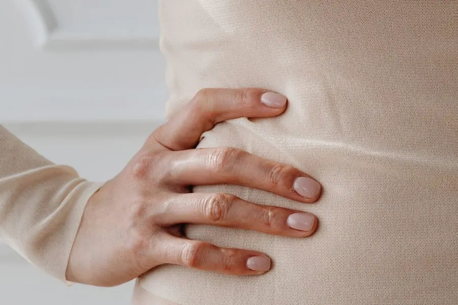 Mulher com a mão apoiada sobre o abdômen, em tons neutros