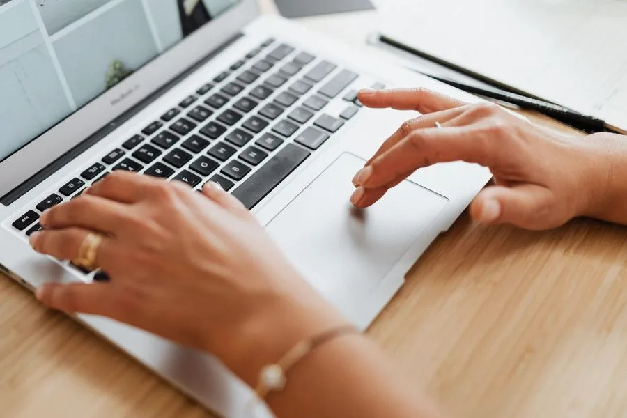 Mãos sobre o teclado de um notebook, consultando informação
